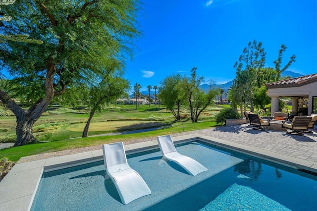 view of swimming pool featuring a patio area, a mountain view, and a yard