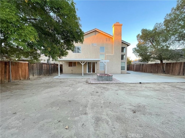 back of property with a patio area and a fire pit