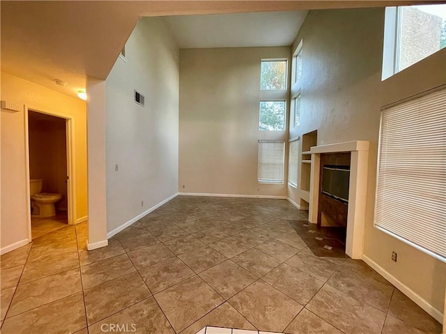 unfurnished living room featuring a high ceiling and tile patterned floors