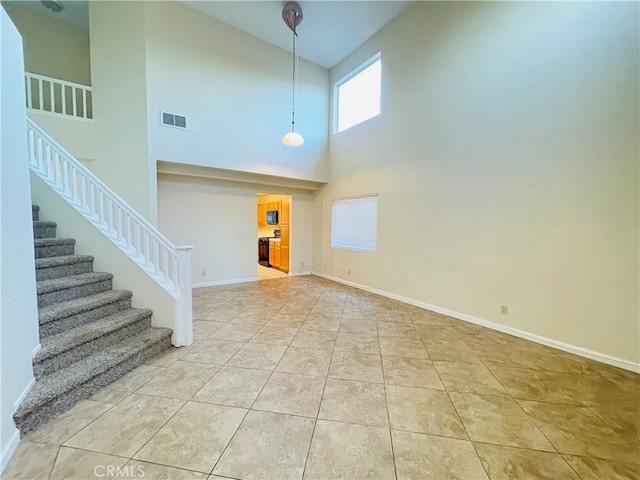 entryway featuring light tile patterned floors and a towering ceiling