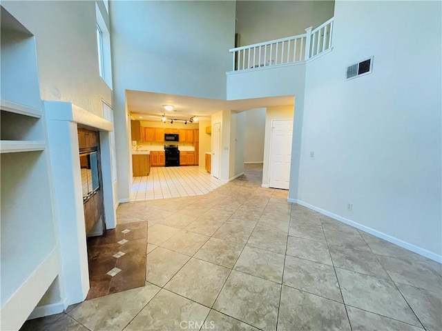 unfurnished living room featuring tile patterned flooring and a high ceiling