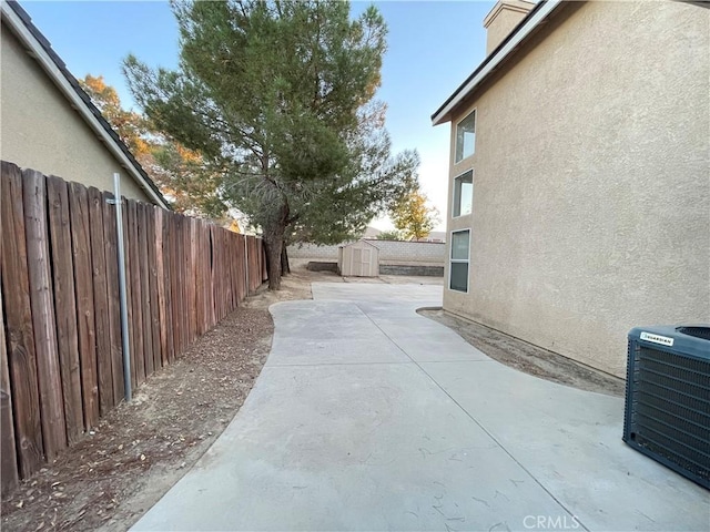 view of side of home with central air condition unit, a patio area, and a storage shed