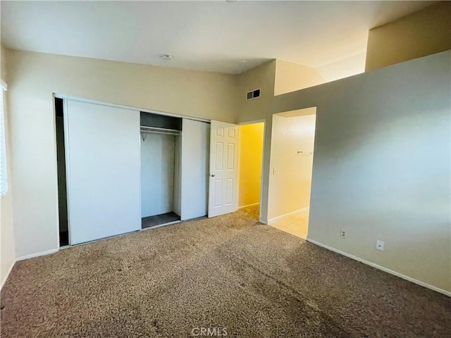 unfurnished bedroom featuring lofted ceiling, light carpet, and a closet