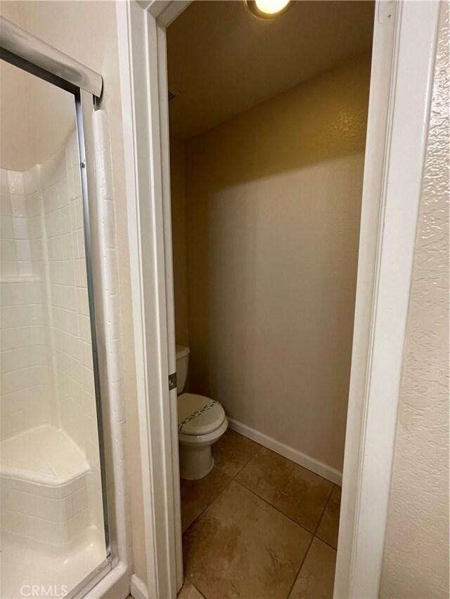 bathroom featuring tile patterned floors, an enclosed shower, and toilet