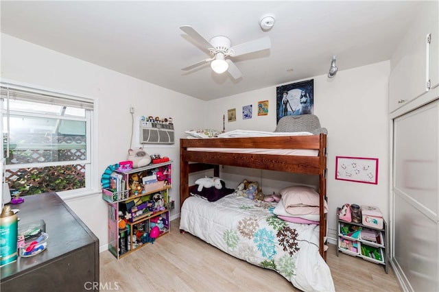 bedroom featuring a wall mounted air conditioner, light wood-type flooring, and ceiling fan