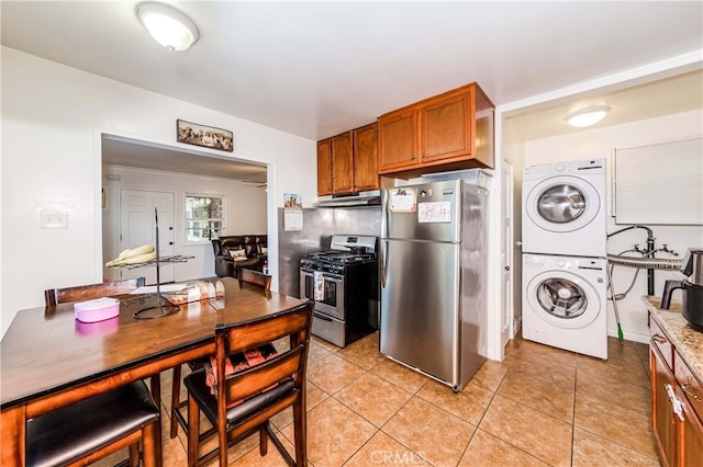 kitchen featuring light tile patterned floors, stainless steel appliances, and stacked washer and dryer