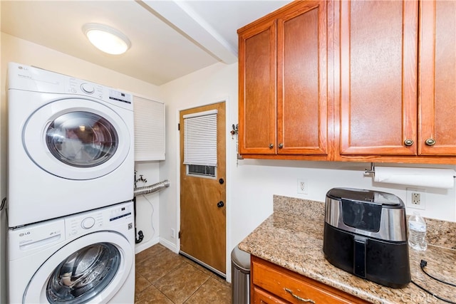 washroom with light tile patterned floors, cabinets, and stacked washer and dryer