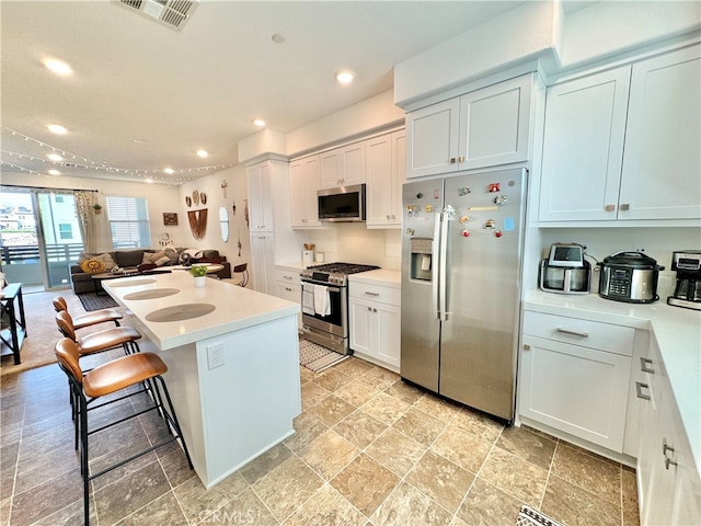 kitchen featuring stainless steel appliances, a center island, a kitchen bar, and white cabinets