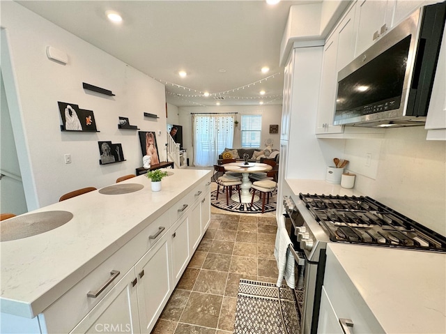 kitchen with white cabinetry, light stone counters, appliances with stainless steel finishes, and a kitchen island