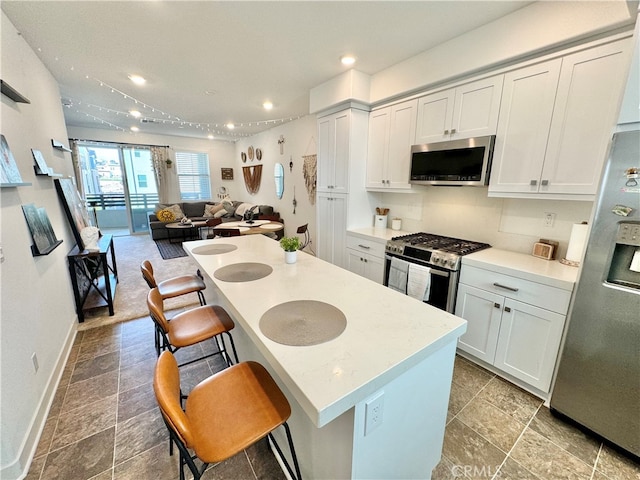 kitchen featuring a breakfast bar, white cabinets, a center island, and stainless steel appliances