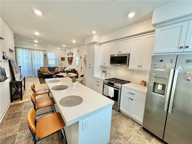 kitchen featuring a kitchen island, white cabinetry, a kitchen breakfast bar, and stainless steel appliances