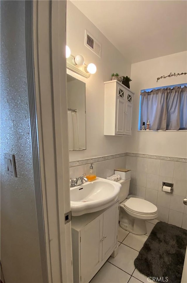 bathroom featuring a shower with curtain, tile patterned flooring, toilet, vanity, and tile walls