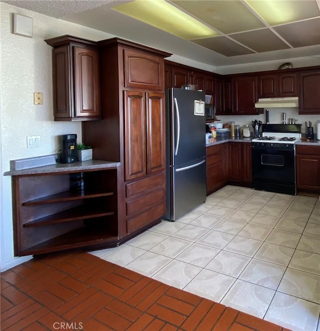 kitchen featuring dark brown cabinetry, white gas range, and stainless steel refrigerator