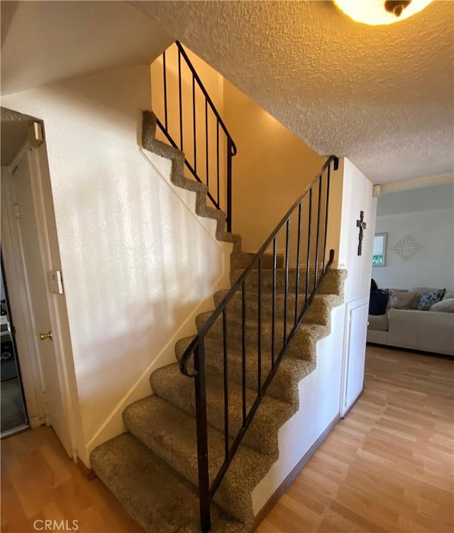 staircase with hardwood / wood-style flooring and a textured ceiling