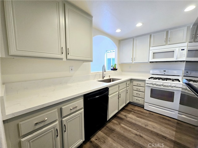 kitchen with dark hardwood / wood-style floors, sink, light stone counters, and white appliances