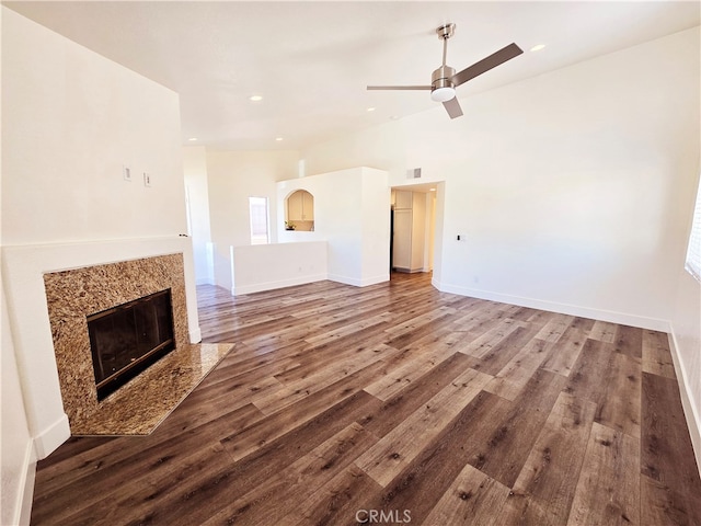 unfurnished living room featuring a premium fireplace, hardwood / wood-style flooring, vaulted ceiling, and ceiling fan