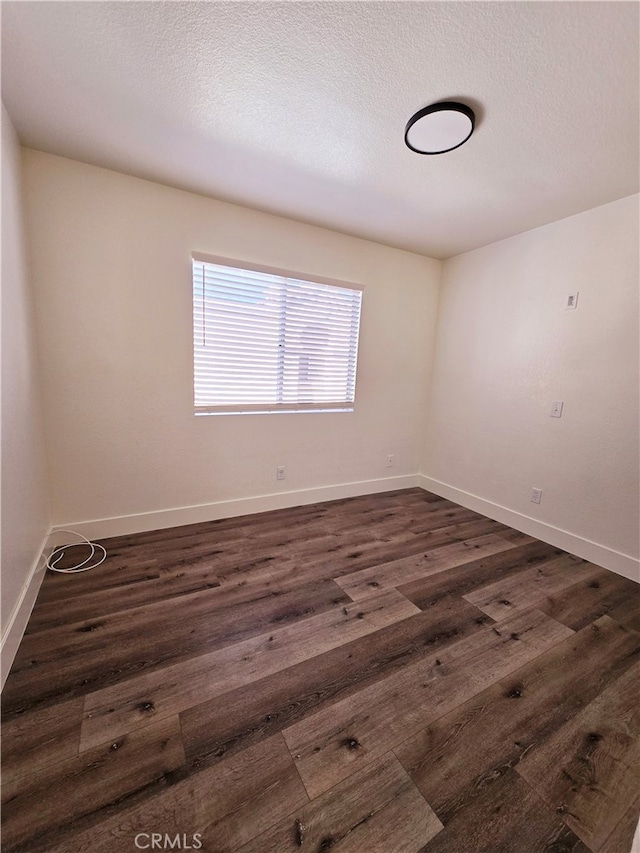 empty room featuring a textured ceiling and dark hardwood / wood-style flooring