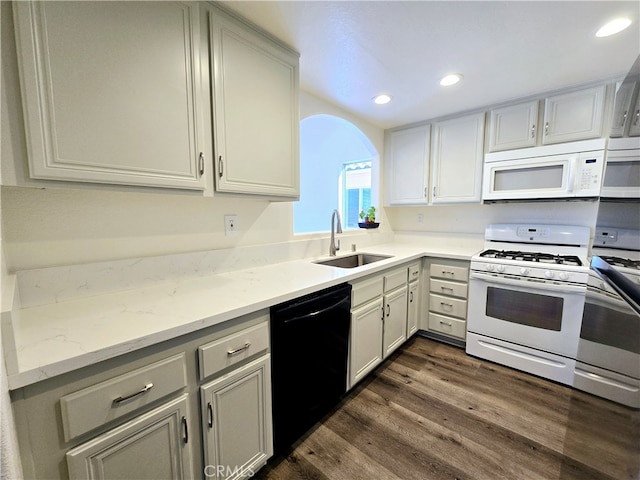 kitchen with dark hardwood / wood-style floors, sink, light stone counters, and white appliances