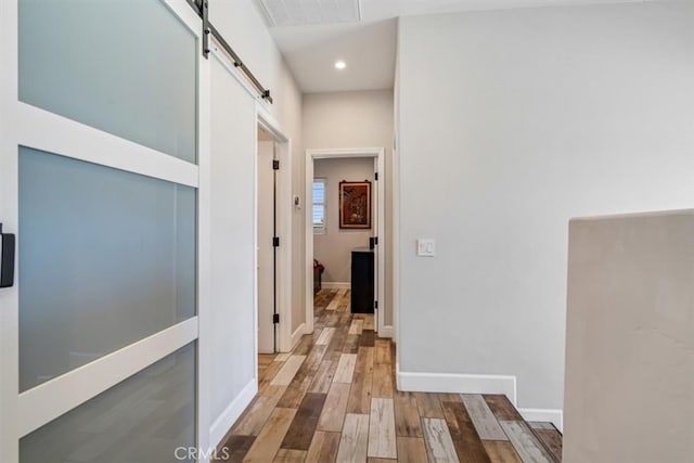 hallway with a barn door and light hardwood / wood-style flooring