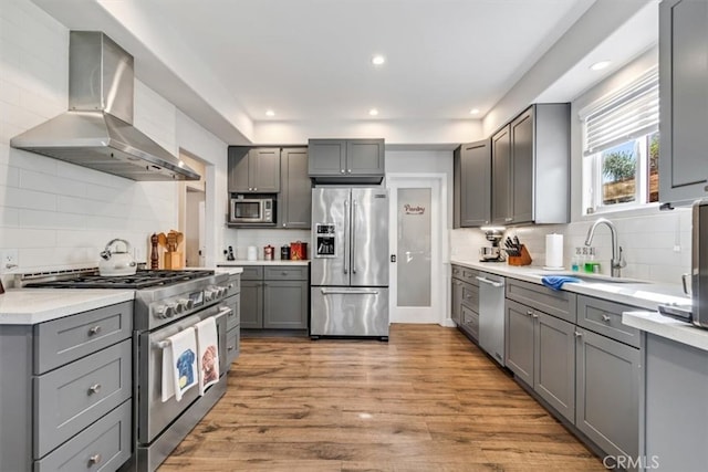 kitchen with extractor fan, light hardwood / wood-style floors, sink, gray cabinets, and high quality appliances