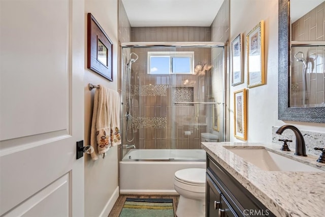 full bathroom featuring combined bath / shower with glass door, vanity, and toilet