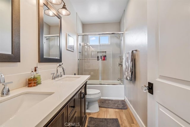 full bathroom featuring bath / shower combo with glass door, wood-type flooring, toilet, and vanity