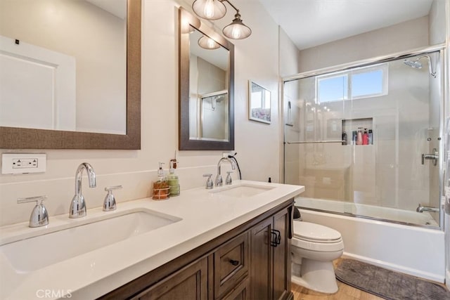 full bathroom featuring bath / shower combo with glass door, toilet, vanity, and hardwood / wood-style floors