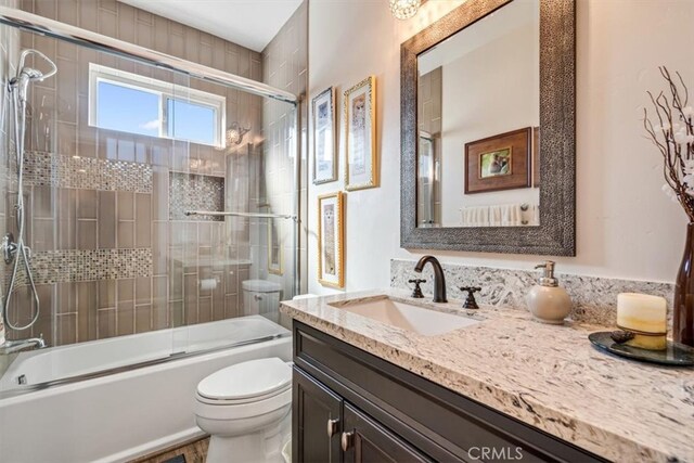 full bathroom featuring bath / shower combo with glass door, toilet, and vanity