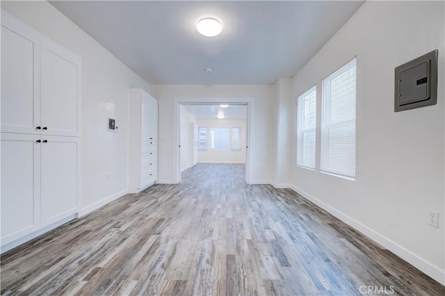 empty room featuring electric panel, baseboards, and wood finished floors