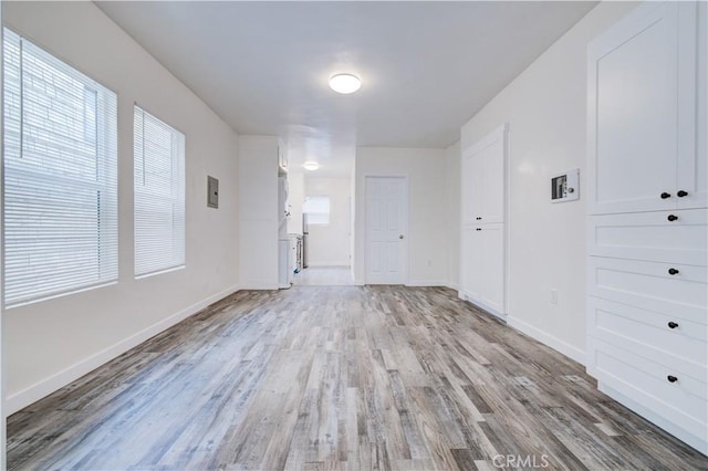 interior space with a wealth of natural light, light wood-type flooring, and baseboards