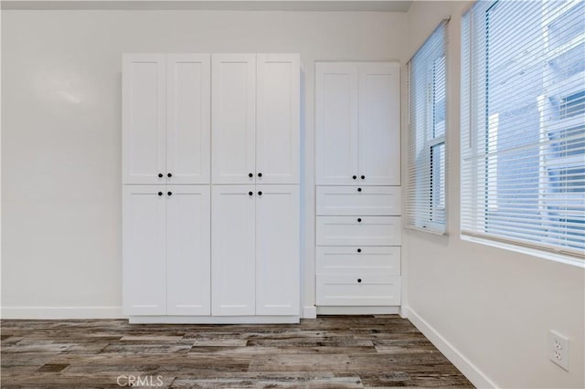 unfurnished bedroom featuring a closet, baseboards, and dark wood-style flooring