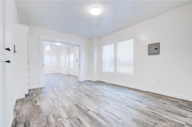 empty room featuring electric panel and light hardwood / wood-style floors