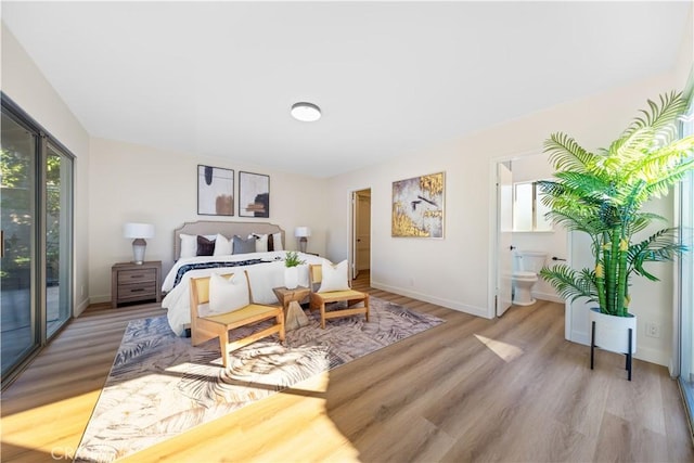 bedroom with light hardwood / wood-style flooring, access to outside, and connected bathroom