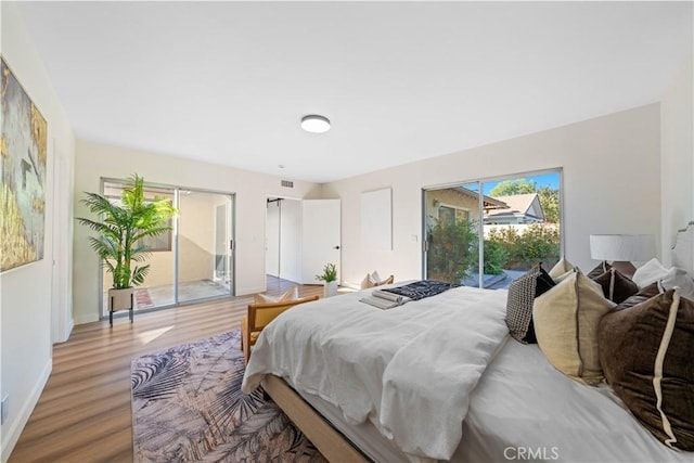 bedroom with access to outside and hardwood / wood-style flooring