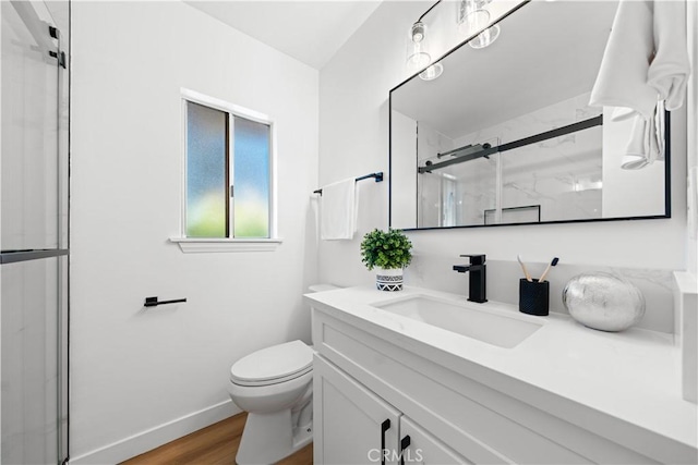 bathroom with wood-type flooring, vanity, toilet, and a shower with shower door