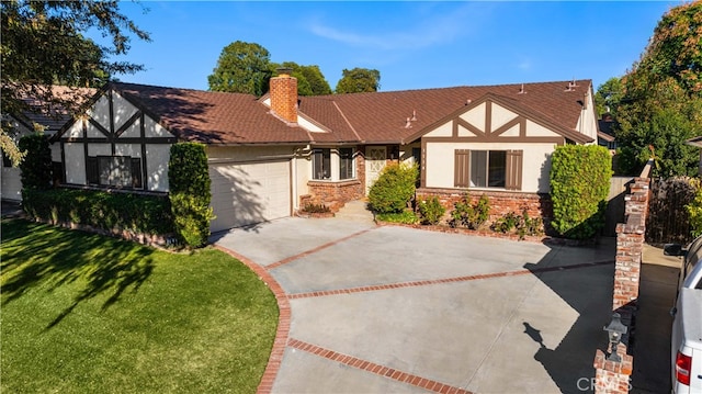 tudor-style house featuring a front yard and a garage