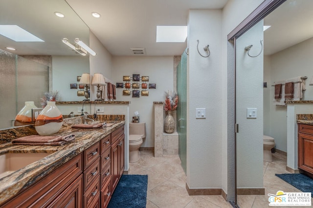 bathroom featuring vanity, a skylight, tile patterned flooring, toilet, and a shower with shower door