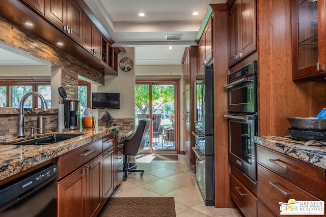 kitchen featuring stone counters, black dishwasher, a wealth of natural light, and sink