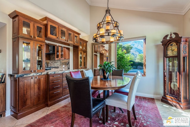 dining area featuring a chandelier, light tile patterned floors, vaulted ceiling, and crown molding