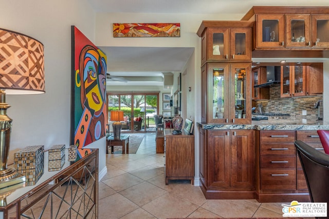 kitchen with light tile patterned floors, backsplash, and light stone counters