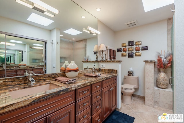 bathroom featuring tile patterned floors, vanity, toilet, and a shower with door