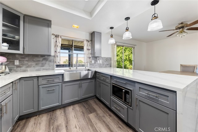 kitchen with kitchen peninsula, gray cabinetry, a healthy amount of sunlight, and tasteful backsplash