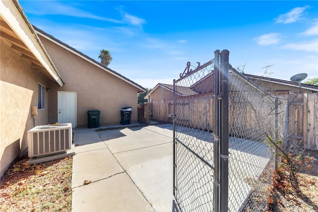 view of gate with central air condition unit and a patio