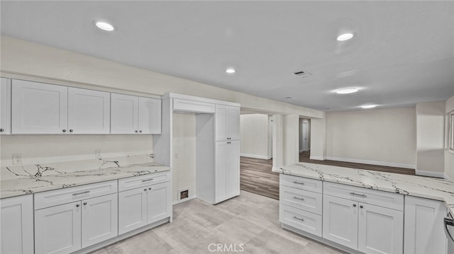 kitchen with light hardwood / wood-style floors, white cabinetry, and light stone counters