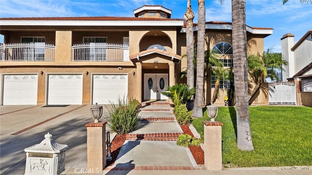 view of property with a balcony, a front lawn, and a garage