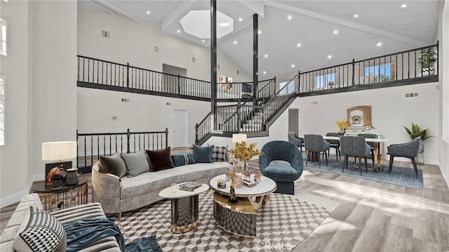 living room featuring beam ceiling, light hardwood / wood-style flooring, and high vaulted ceiling