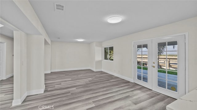 empty room featuring french doors and light hardwood / wood-style flooring