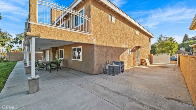 back of property with a balcony, cooling unit, a patio, and ceiling fan