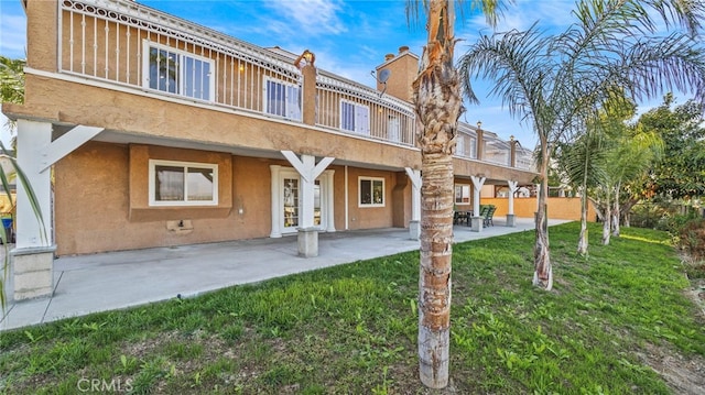 rear view of property featuring a patio, a lawn, and french doors