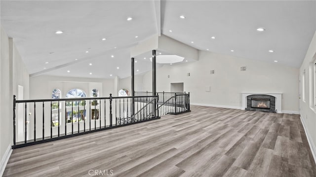 unfurnished living room featuring high vaulted ceiling, a premium fireplace, light hardwood / wood-style flooring, and beamed ceiling